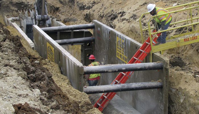 Two Carter Cat employees working inside a steel trench box with a red ladder inside of it